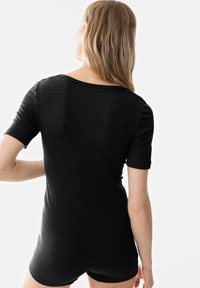 Černé pruhované tričko s krátkým rukávem, se volným střihem a širokým výstřihem, které vyniká hladkou texturou a jednoduchým designem.