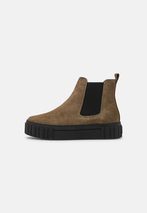 Brauner Chelsea-Stiefel aus Wildleder mit schwarzem elastischem Seiteneinsatz und dicker schwarzer Gummisohle, im Profil gezeigt.
