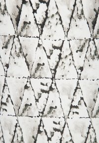 Textilmönster med svarta och vita trianglar i en texturerad yta, med ojämn skuggning och bläcklika märken.