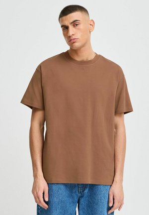 Brown short-sleeve t-shirt made of cotton with a crew neckline, paired with blue denim jeans, displayed on a neutral background.