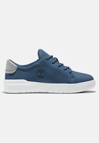 Zapatillas sintéticas azules con parte superior texturizada, entresuela blanca y acento en el talón gris. Presenta un logo en el lateral y cordones redondos.