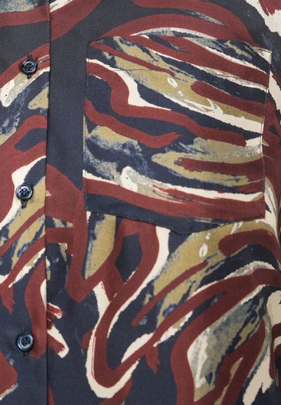 Kortærmet skjorte i mørkt stof med iøjnefaldende abstrakte mønstre i rød, beige og blå, med en brystlomme og runde knapper.