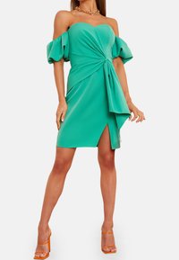 Zielona sukienka bez ramiączek z bufiastymi rękawami i skręconym węzłem w talii, z bocznym rozcięciem i gładką fakturą.