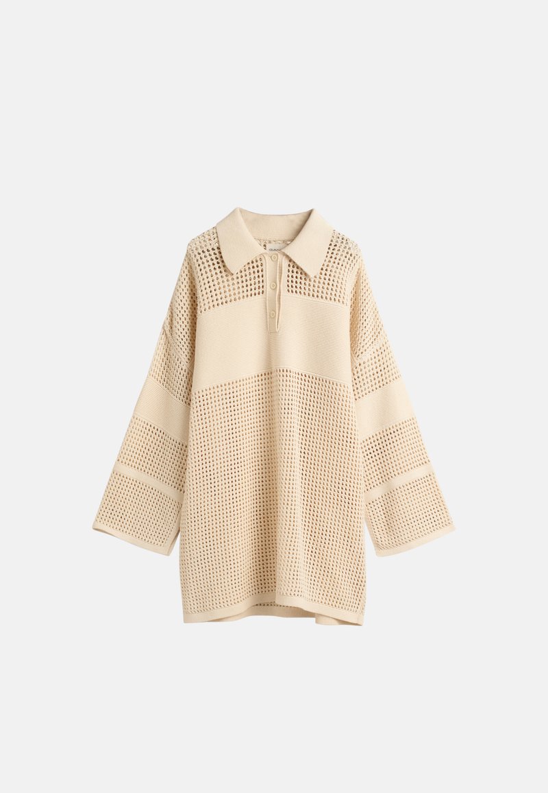 Beżowy sweter z dzianiny z kołnierzykiem, z teksturowanym wzorem i szerokimi rękawami. Projekt obejmuje sekcje w stylu siatki oraz gładkie paski.