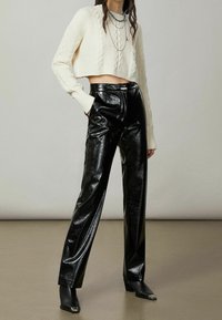 Kermaköynnöksinen lyhyt neulepaita, joka on yhdistetty korkean vyötärön mustiin kiiltäviin mokkanahkahousuihin. Saappaissa on neliönmuotoinen kärki.