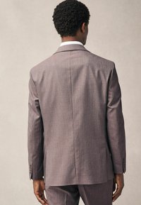 Grauer strukturierten Anzugjacke mit einem Schlitz, langen Ärmeln und geknöpften Manschetten, von hinten betrachtet. Glattes Material.