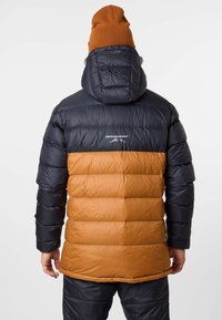 Vadderad jacka med en marinblå ovandel och orange nederdel. Har en huva, kviltad textur och ett varumärkeslogotyp på baksidan.