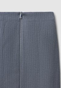 Jupe crayon grise sur mesure avec des rayures verticales, dotée d'une fermeture éclair métallique à l'avant et d'une texture de tissu lisse.