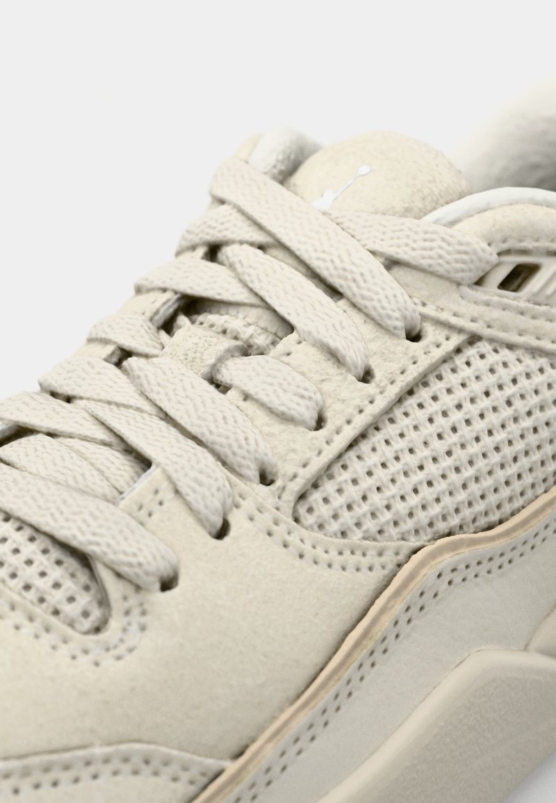 Zapatillas beige con parte superior de ante y malla, cordones planos y suela de goma texturizada con un sutil detalle del logo en la lengua.