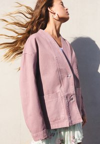 Roze katoenen jas met een ruime pasvorm, V-hals, twee steekzakken aan de voorkant en een enkele knoopsluiting. Soepele textuur, casual stijl.