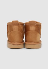 Stivaletti alla caviglia in suede marrone con accenti in tessuto e lati testurizzati, dotati di una linguetta rinforzata sul tallone e una suola in gomma beige.