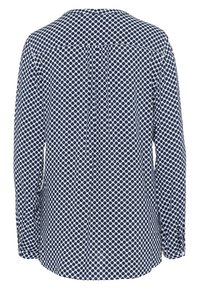 Camicia a maniche lunghe a pois blu navy e bianchi con colletto standard, piega posteriore e polsini con bottoni. Tessuto morbido e leggero con una texture liscia.
