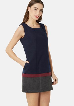 Vestido sin manga de color marino con escote cuadrado, acento de dobladillo en burdeos, parte inferior gris y bolsillos. Tejido suave con un diseño ajustado.