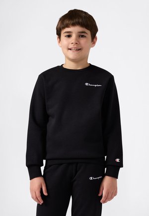Sudadera negra de tejido suave con cuello redondo y mangas largas. Presenta el logo blanco de "Champion" en el pecho y la manga.