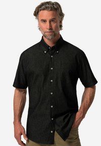 Svart kortärmad skjorta med knappar i en strukturerad tyg, med en bröstficka och kontrasterande vita knappar.