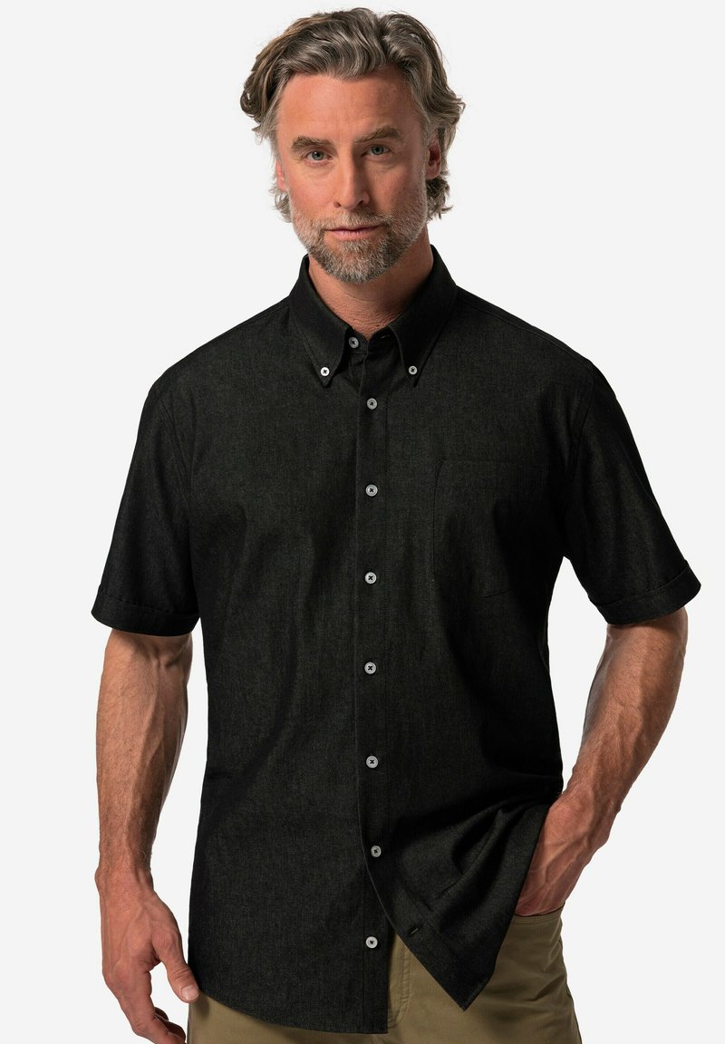 Svart kortärmad skjorta med knappar i en strukturerad tyg, med en bröstficka och kontrasterande vita knappar.