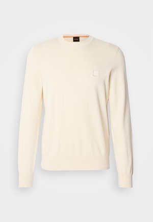 Cremfarbener Pullover mit Rundhalsausschnitt, langen Ärmeln und kleinem quadratischen Logo auf der Brust. Aus weichem, hochwertigem Stoff gefertigt.