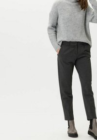 Harmaa neule korkean kaula-aukko kanssa, yhdistetty tummanharmaisiin, räätälöityihin suoriin housuihin. Mallilla on nilkkurit.