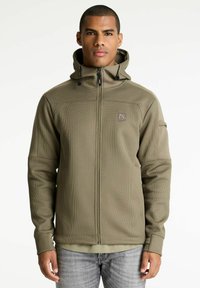 Maslinasto zelena zip-up dukserica s teksturiranom tkaninom, podesivim kapuljačom i dva bočna džepa. Ima logotip na prsima.