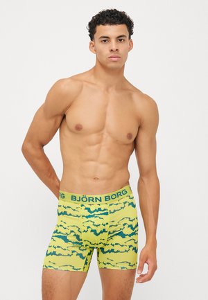 Gelbe Boxershorts mit grünem abstraktem Muster, elastischem Bund mit 'BJÖRN BORG'-Branding, eng anliegendem Schnitt und glatter Textur.