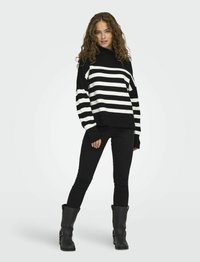 Zwart-wit gestreepte sweater met hoge hals, losse pasvorm en lange mouwen. Gepaard met zwarte skinny jeans en hoge zwarte laarzen.