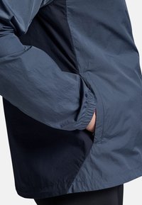 Marine windbreaker jas met een textuurafwerking, voorzien van een zijzak en elastische manchetten, ontworpen voor optimaal comfort en beweging.