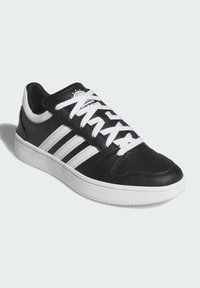 Čierne kožené tenisky s bielymi pruhmi, bielymi šnúrkami a bielou podrážkou. Obsahujú perforácie pre priedušnosť a hladký povrch.