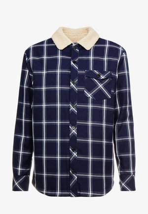 Navy-kariertes Hemd mit weißen und hellblauen Linien; verfügt über einen cremefarbenen Kunstfellkragen und eine Brusttasche mit einem schwarzen Knopf.