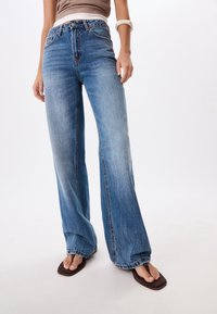 Wide-leg denim jeans in light blue wash, featuring a high waist, classic five-pocket design, and subtle fading for texture.