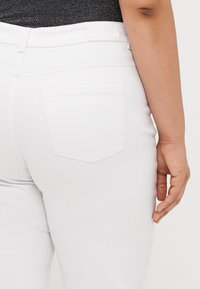 Λευκά τζιν παντελόνια από πίσω, με μία μόνο πίσω τσέπη, υπ subtle ραφές και απαλή υφή.