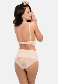 Spetsbh och höga trosor i ljusbeige. Har intrikata blommönster, justerbara band och en hakknäppning i ryggen.