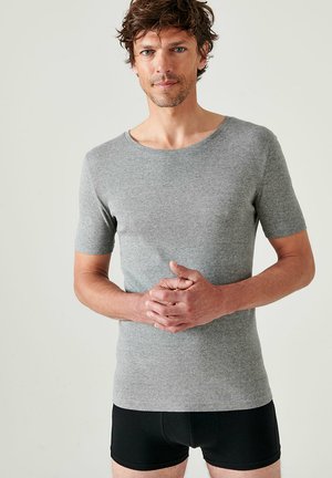 T-shirt gris à manches courtes en matière douce, avec un col rond et un design ajusté, porté avec un short en boxer noir.