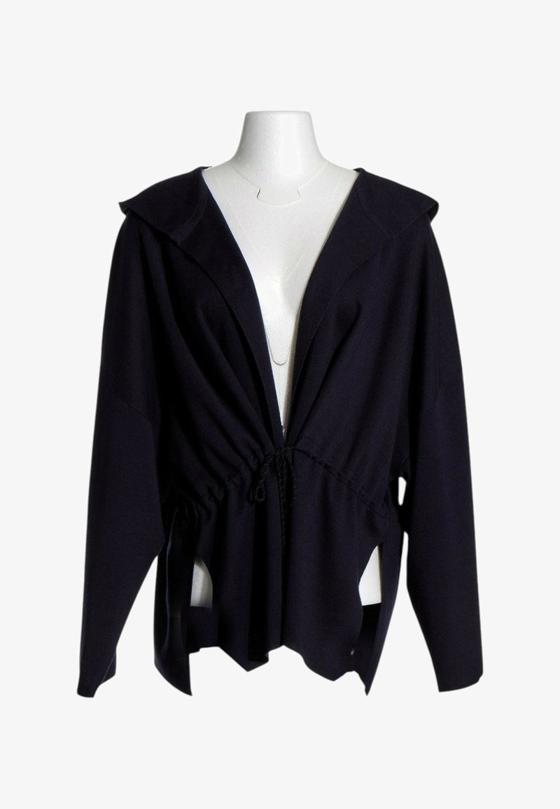 Veste noire à manches longues avec large col et taille à cordon, présentée sur un torse de mannequin blanc sur fond blanc.
