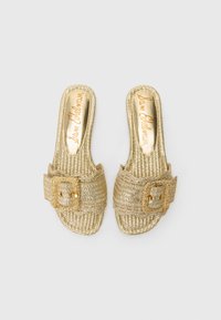 Gold woven slide sandals with a rounded toe, featuring a decorative buckle and a textured sole. Branding on insole is also gold.