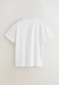 Bílý krátký rukáv tričko z bavlny. Má kulatý výstřih a rovný lem s čistými švy. Hladká textura, minimalistický design.