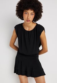 Vestido preto com mangas curtas e franzidas e saia rodada. Textura suave, cintura ajustada e detalhes de bainha em camadas.