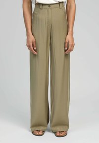 Pantalons larges en tissu vert olive, avec une taille haute, des passants de ceinture et des poches latérales. Texture lisse et coupe pleine longueur.