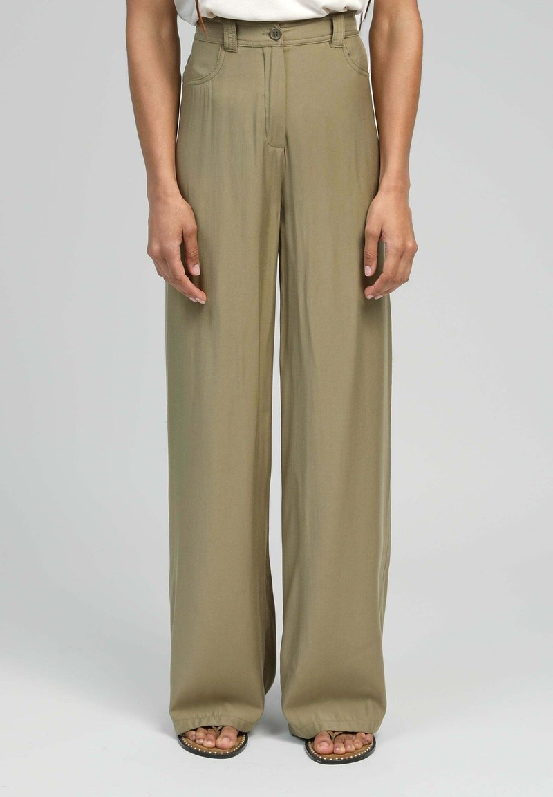 Pantalons larges en tissu vert olive, avec une taille haute, des passants de ceinture et des poches latérales. Texture lisse et coupe pleine longueur.