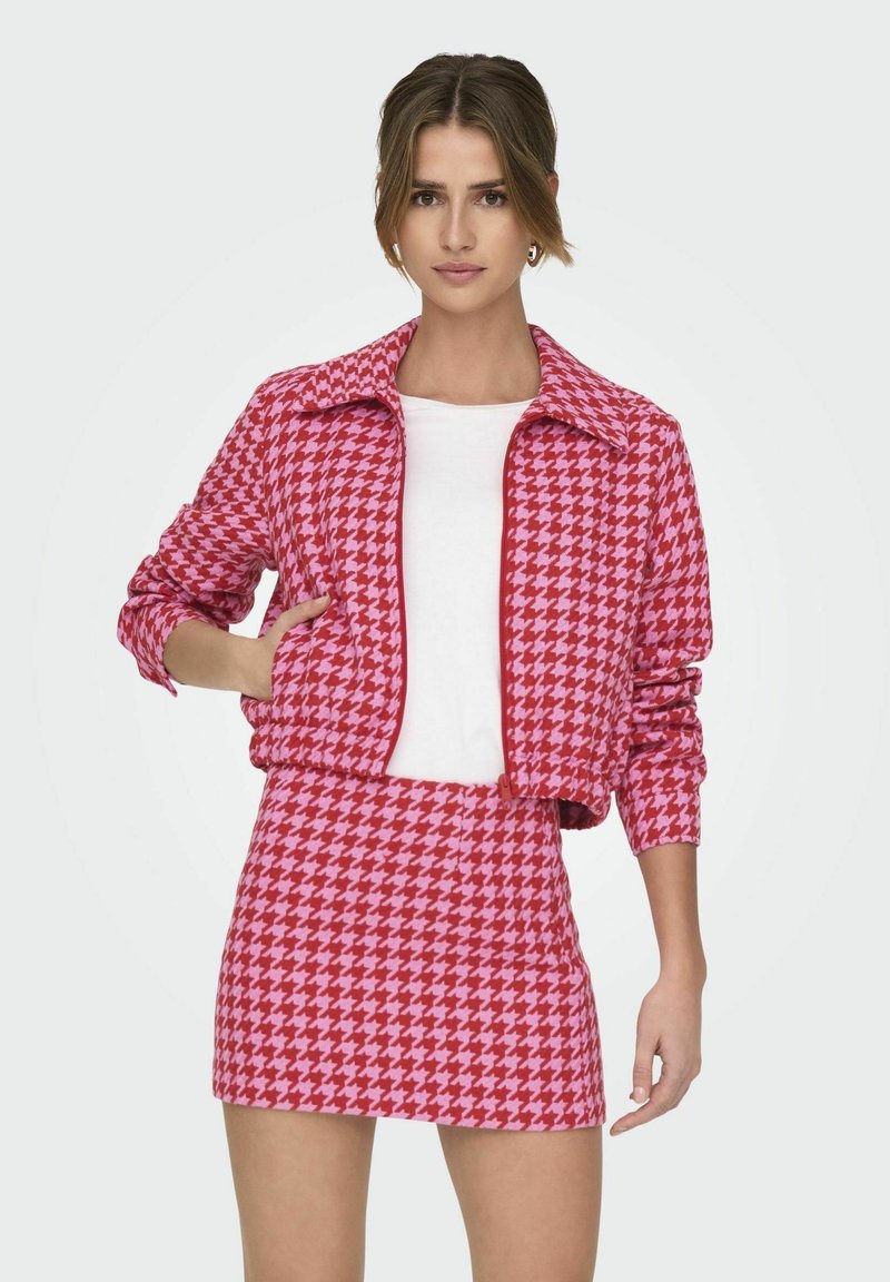 Roze en rode houndstooth-geprinte cropped jack met een kraag, gecombineerd met een bijpassende mini rok, met een gladde textuur.