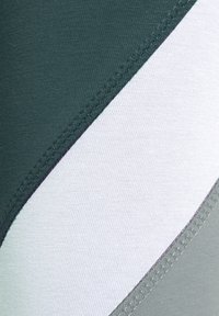 Dark green, white, and light gray fabric swimwear with a smooth texture and diagonal color blocking; features flatlock stitching.