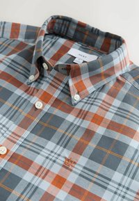 Nööbitav ruuduline särk, mis sisaldab halli, oranži ja valget ruudumustrit, nööbitavat kraed ja väikest tikitud logo rinnal.