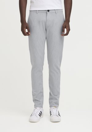 Lys grå skreddersydde bukser med en jevn tekstur, med knappelukking og beltehalser, kombinert med hvite sneakers og svarte striper.