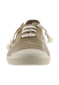 Zapatilla de lona beige con punta redonda, suela de goma blanca y agarre texturizado. Presenta cordones color crema y borlas decorativas a los lados.