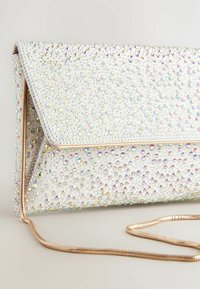 Weiße Clutch mit facettierten Strasssteinen, die die Oberfläche bedecken, goldfarbener Hardware und einem langen Kettenriemen. Strukturierte Form mit Klappenverschluss.
