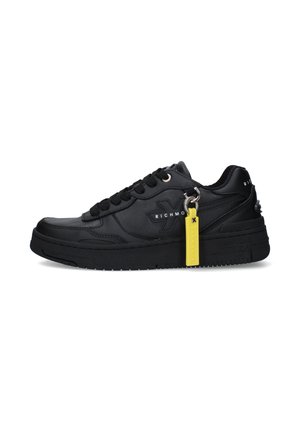 Sneaker nera low-top con suola spessa, lacci neri, logo "Richmond" sul lato e una targhetta gialla attaccata vicino ai lacci.