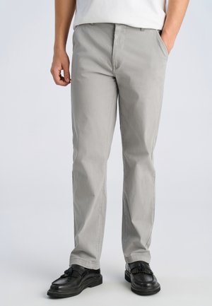 Vaaleanharmaat suorat housut, jotka on valmistettu kevyestä puuvillasta. Housuissa on sivutaskut ja nappisuljenta, yhdistetty mustiin loafer-kenkiin.