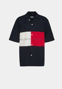 Camicia a maniche corte con design a blocchi di colore in blu navy, rosso e bianco. Include testo con logo, chiusura con bottoni e vestibilità rilassata.