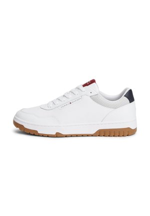 Baskets basses blanches avec semelle en gomme, étiquette rouge sur la languette, languette de talon bleu marine et logo Tommy Hilfiger sur le côté.