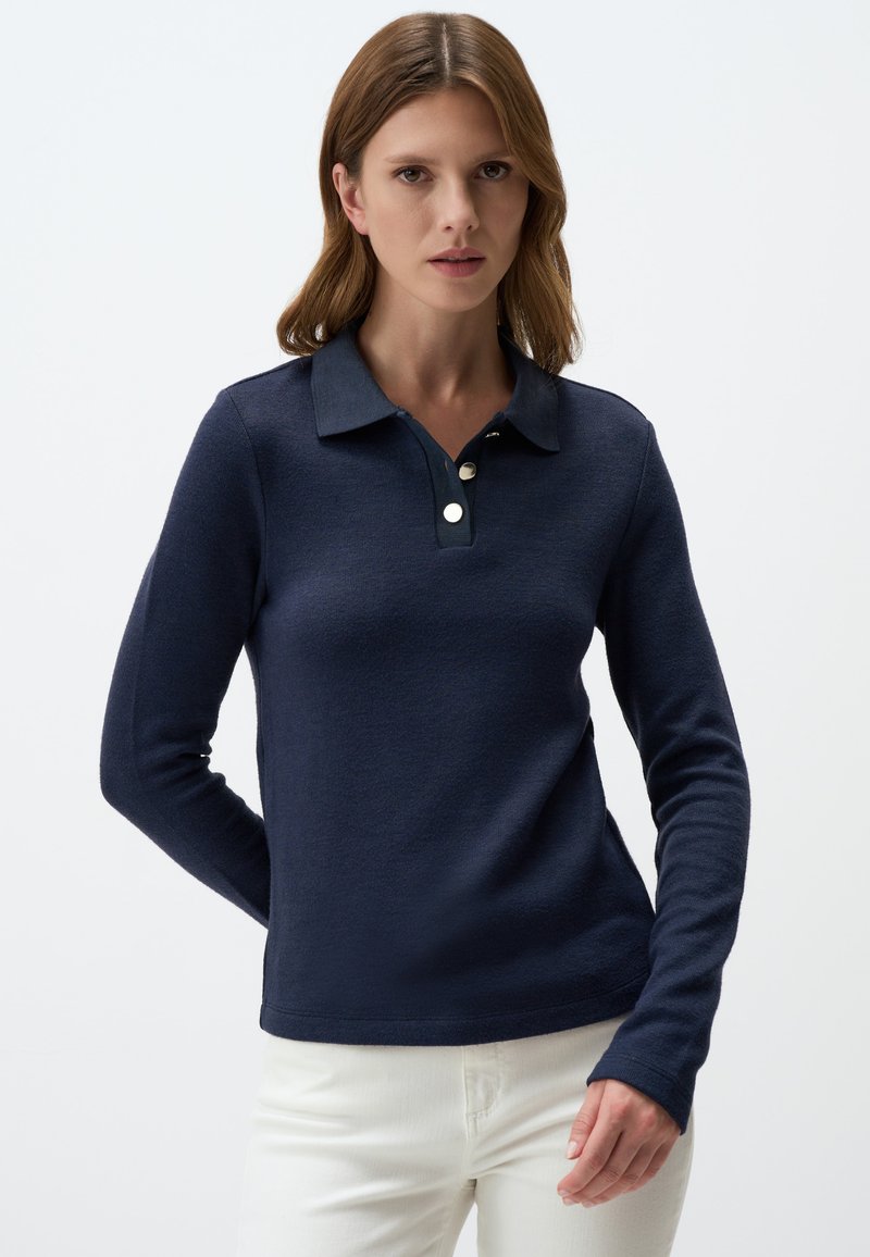 Marineblauw poloshirt met lange mouwen, gemaakt van textuurstof. Beschikt over een klassieke kraag, een placket met drie knopen en een getailleerd ontwerp. Witte knoppen als accent.
