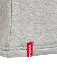 Grijze katoenstof met een gladde textuur, voorzien van een rode "hummel"-label aan de naad. Eenvoudig ontwerp, subtiel gemêleerd patroon aanwezig.